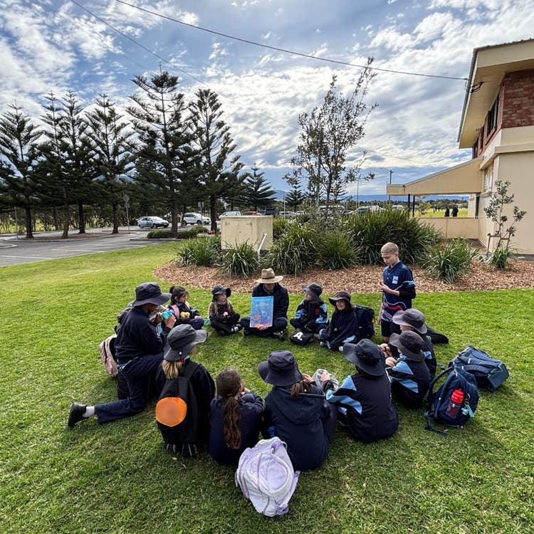 Students in a circle with the teacher reading a story at the NAIDOC excursion